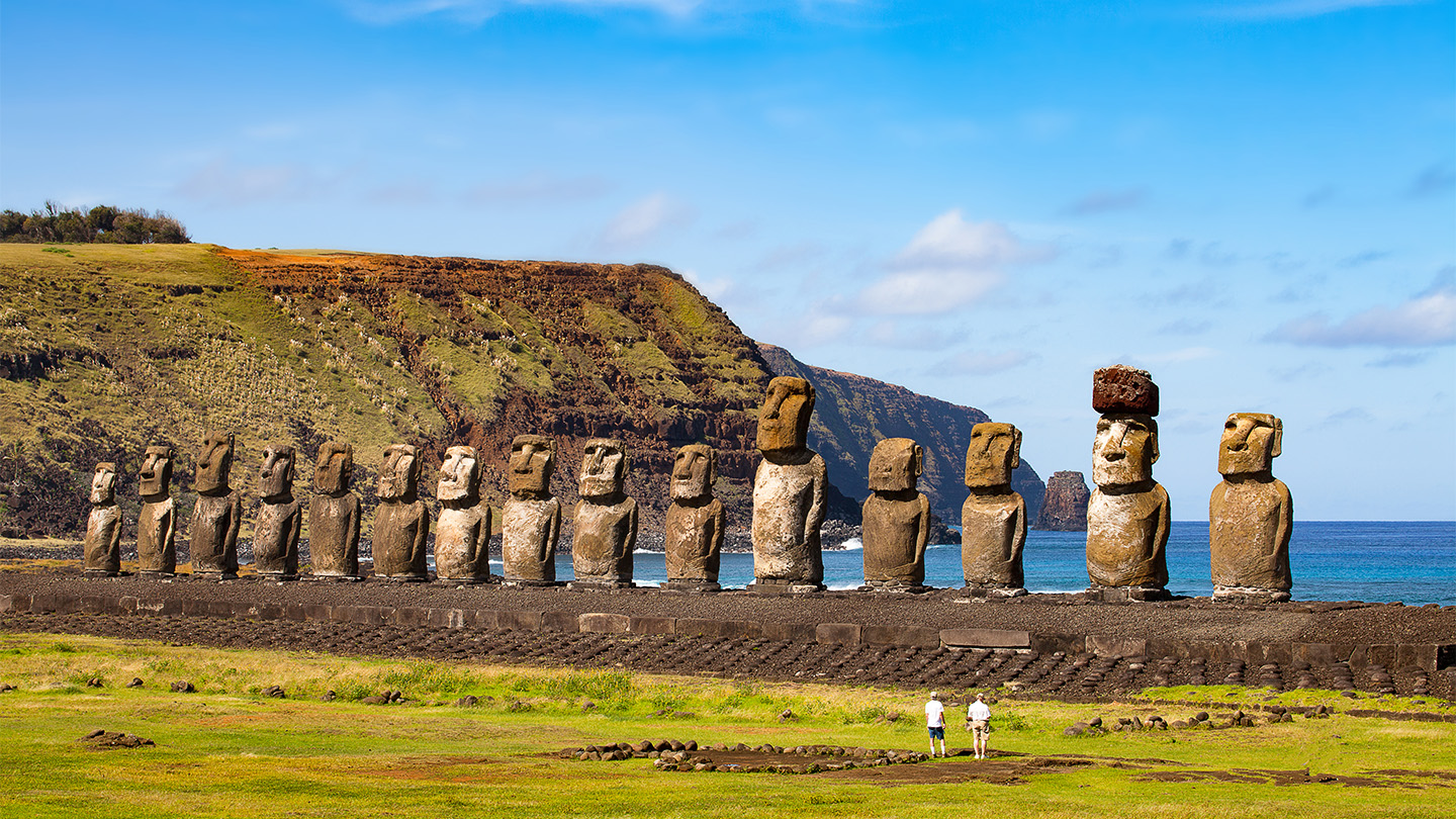 A line of Easter Island's famous stone statues face inland, with their backs to the ocean.